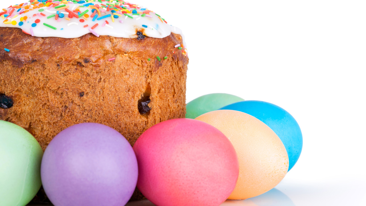 Пасхальный кулич с изюмом на белом фоне с крашеными яйцами 