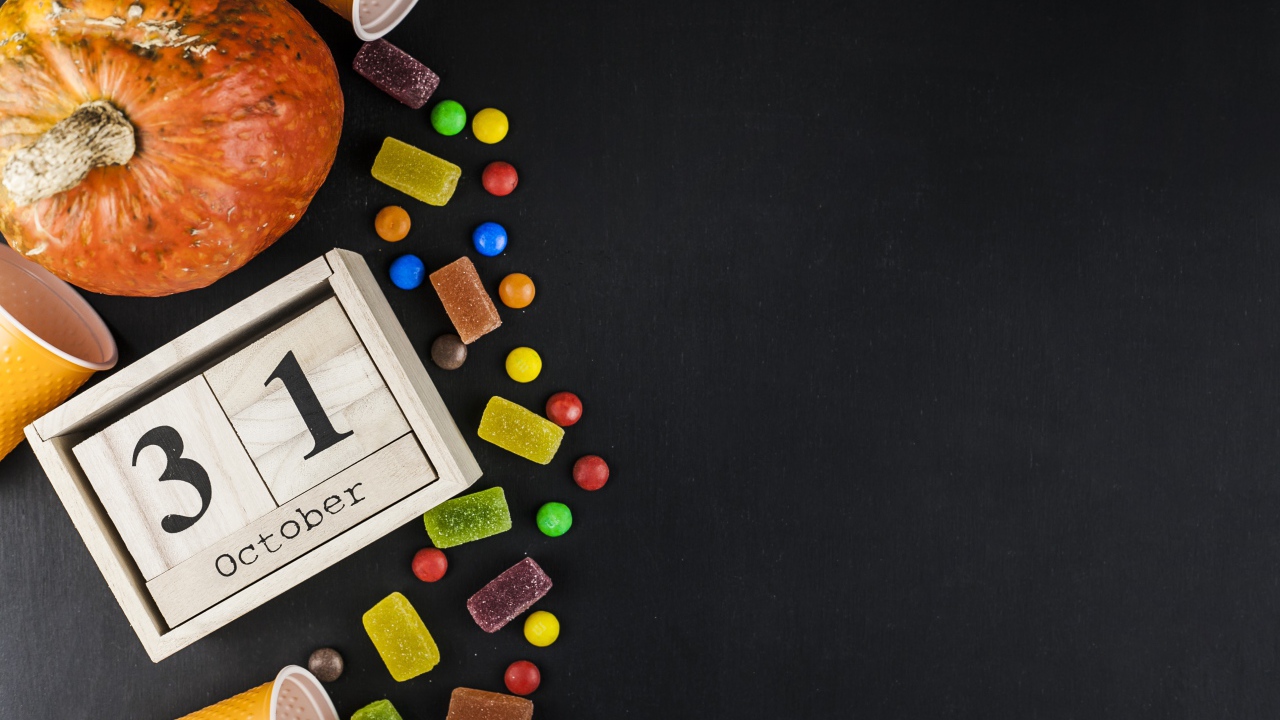 Конфеты, тыква и календарь на сером фоне на Хэллоуин