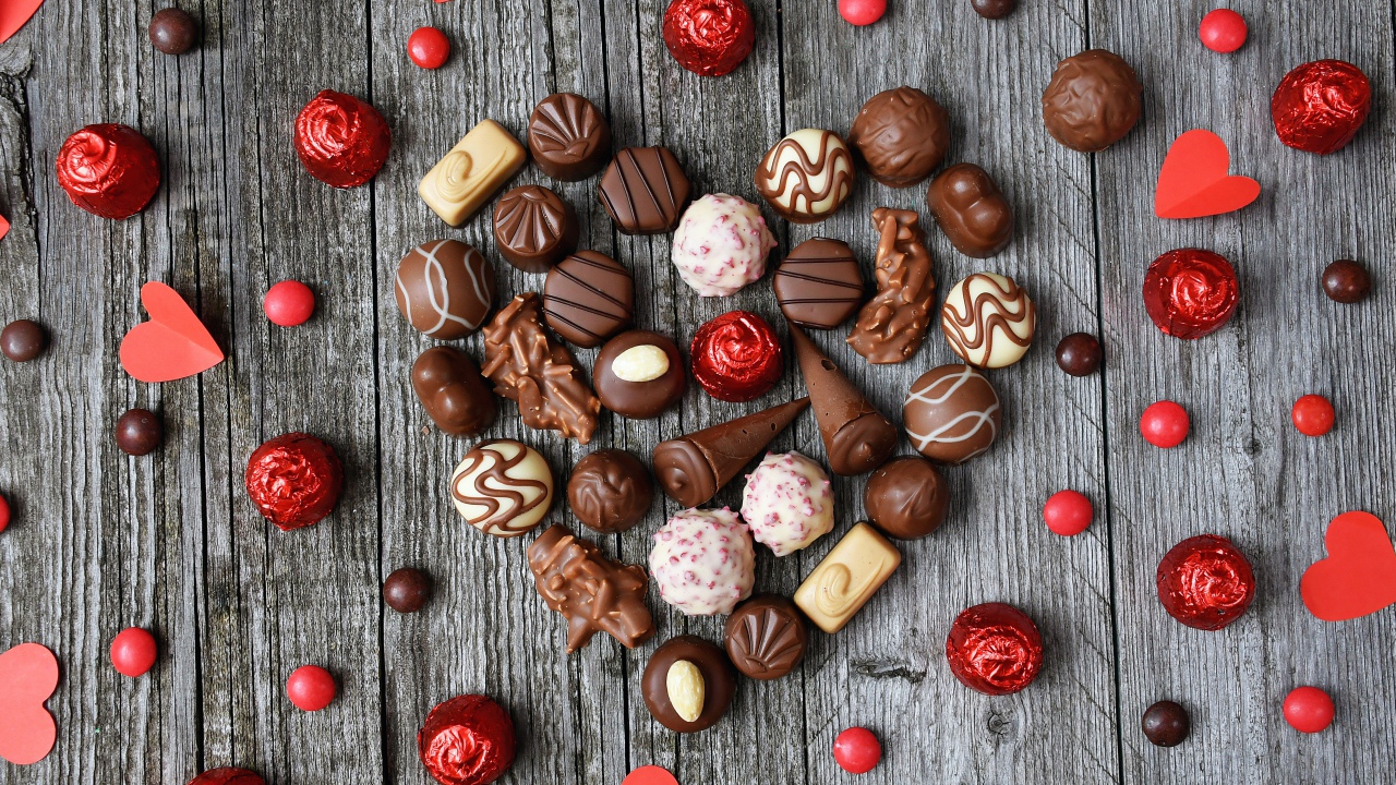 Сердце из шоколадных конфет ассорти на деревянном столе для любимой 
