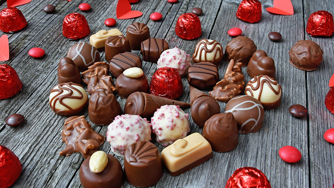 Сладкое сердце из шоколадных конфет на деревянном столе