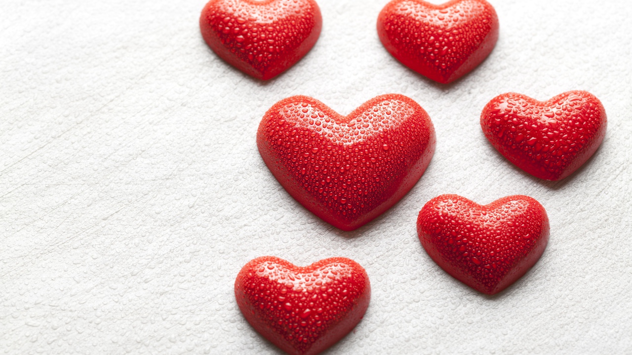 Мокрые красные сердечки на белой поверхности 