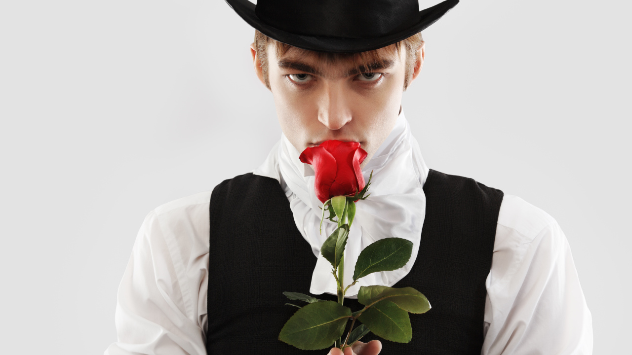 Guy in a top hat with a red rose in his hand on a gray background
