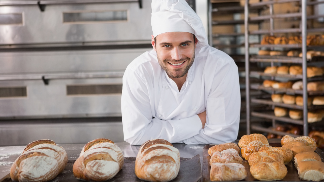Красивый улыбающийся мужчина пекарь в форме