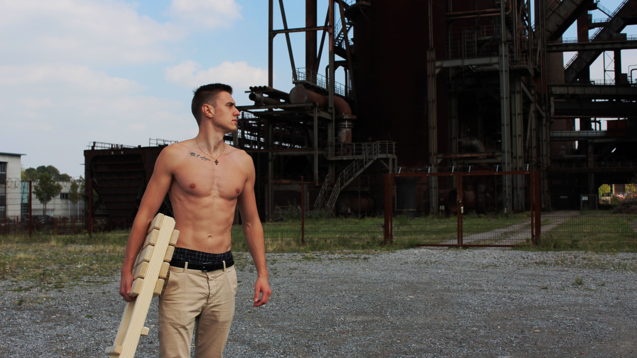 Красивый молодой парень стоит на фоне завода