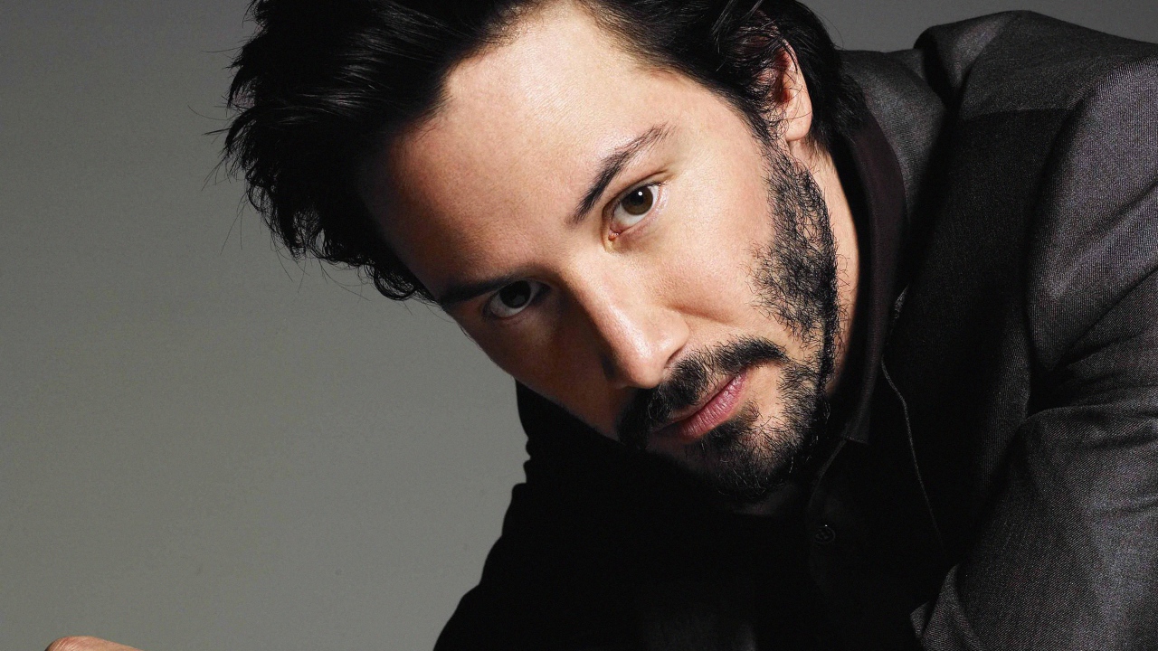 Актер Киану Ривз в костюме на сером фоне