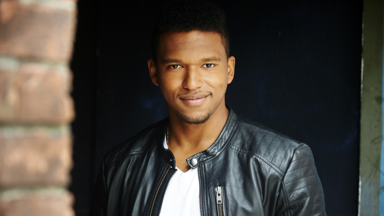 Красивый мужчина в черной куртке, актер Ловелл Адамс-Грей