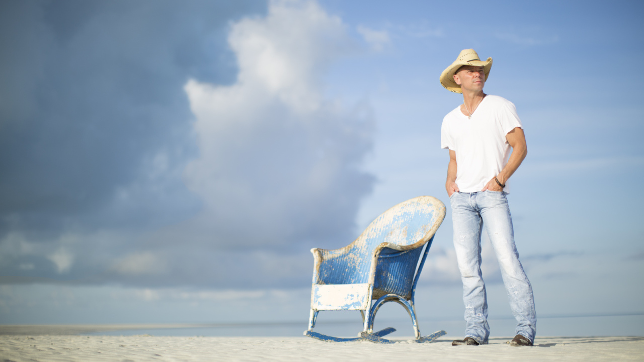 Кантри исполнитель Кенни Чесни в креслом на пляже