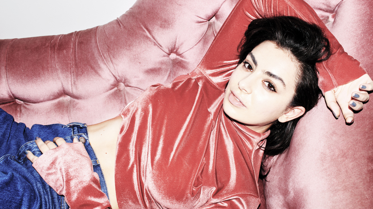 Молодая девушка Charli XCX лежит на диване