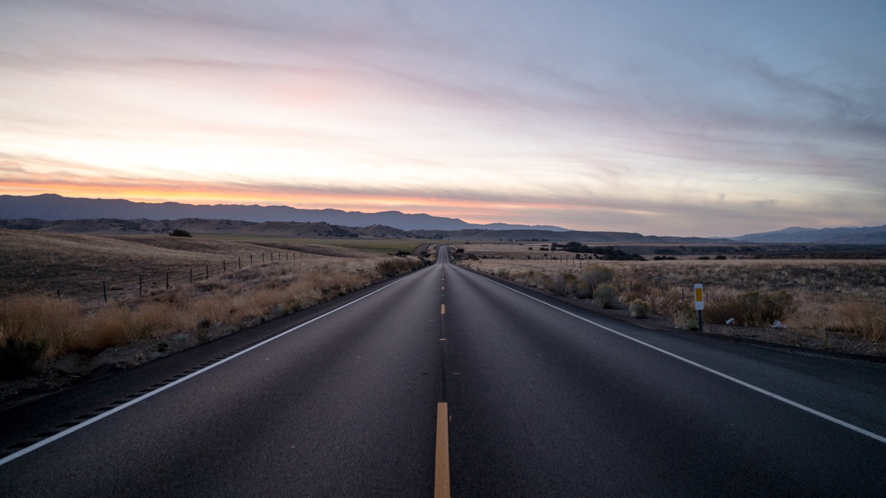 Асфальтная дорога уходит вдаль на фоне неба