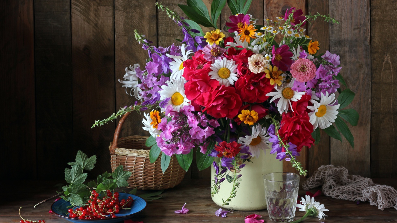 Красивый букет стоит на  столе с красной смородиной