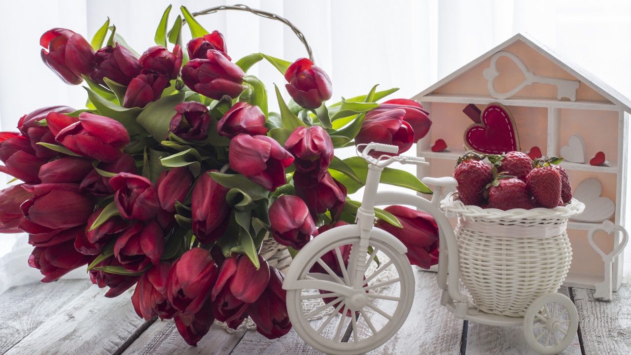 Красивый букет красных тюльпанов на столе с клубникой 