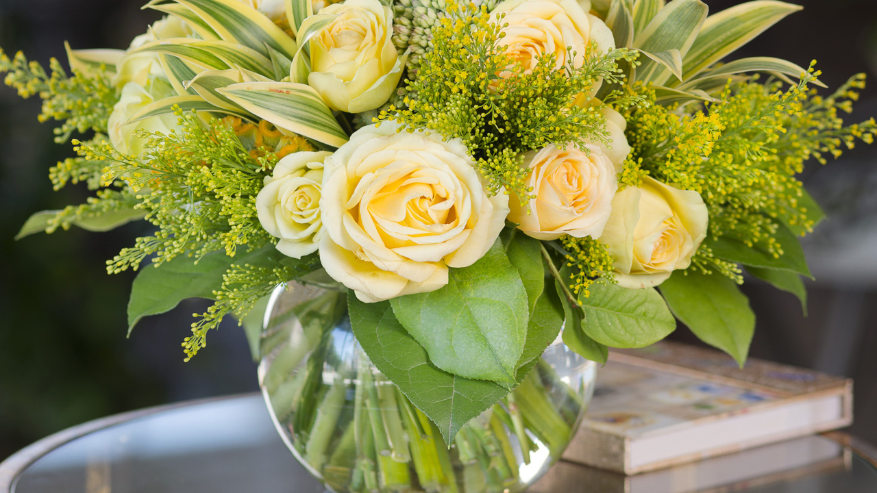 Красивый букет роз с зелеными листьями в в вазе на стеклянном столе