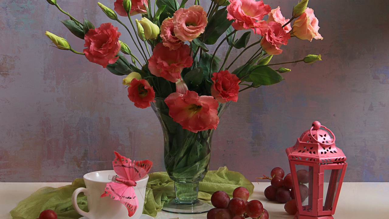 Букет розовых цветов эустомы на столе с виноградом