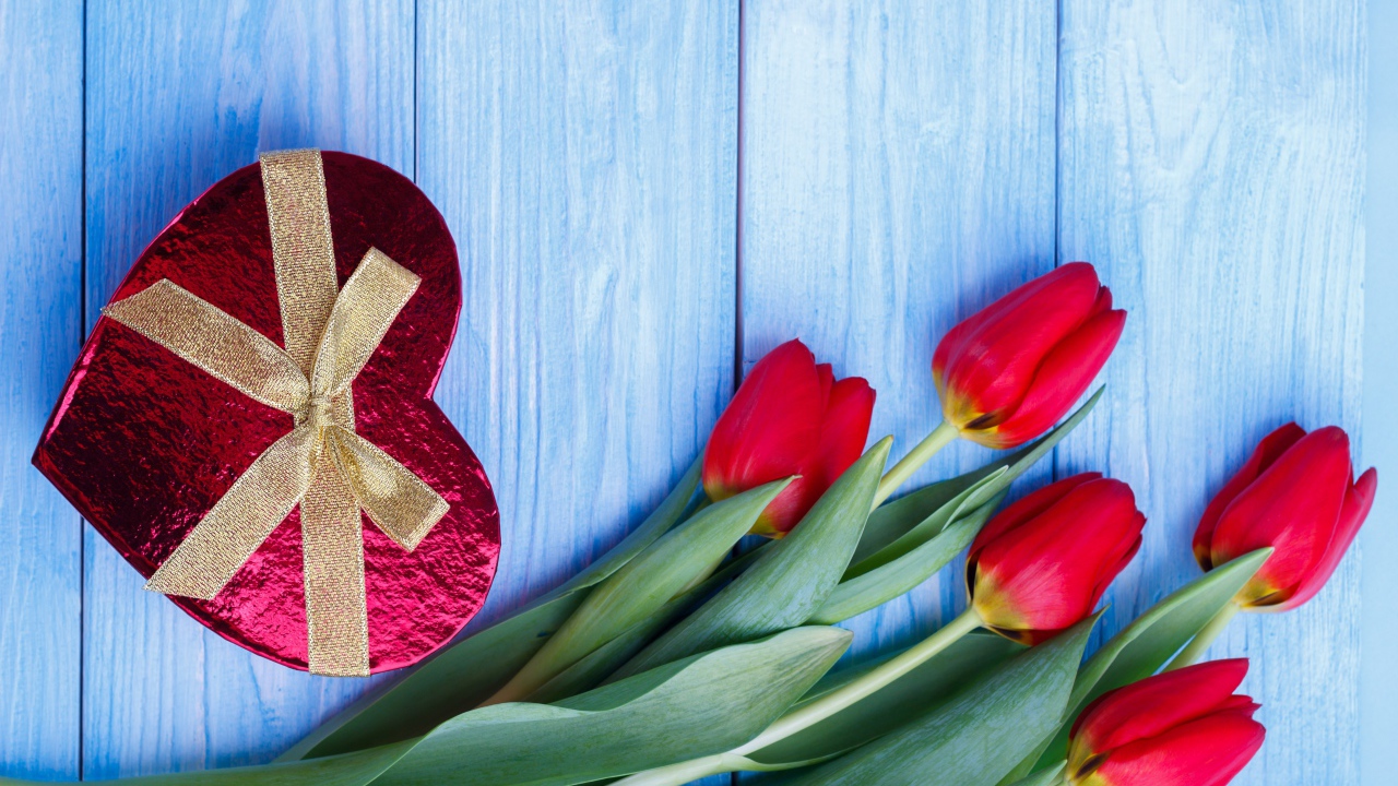 Букет красных тюльпанов на синем фоне с подарком в форме сердца