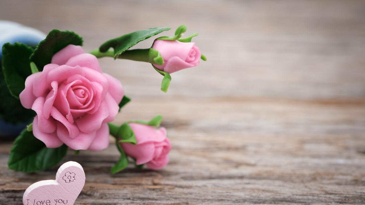Розовые искусственные розы с сердцем на деревянном фоне