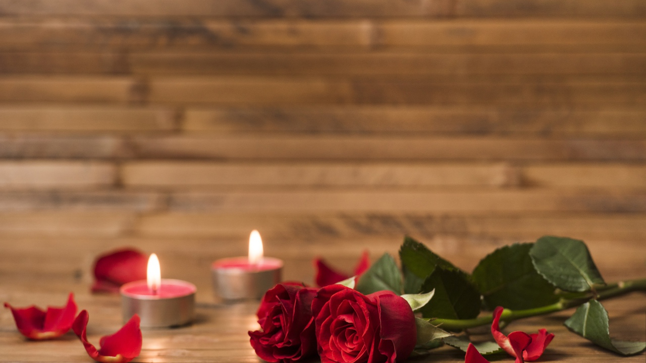 Две красные розы на столе с зажженными свечами 