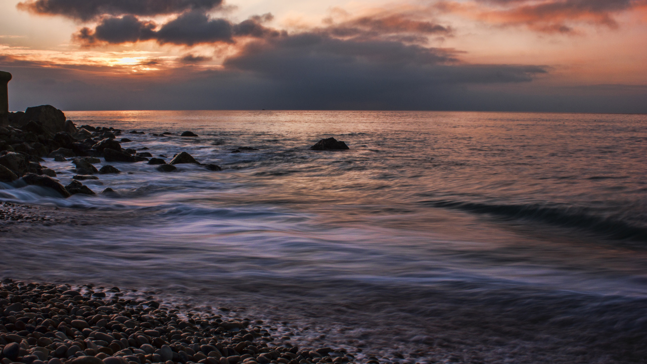 Мелкие камни на берегу моря на закате