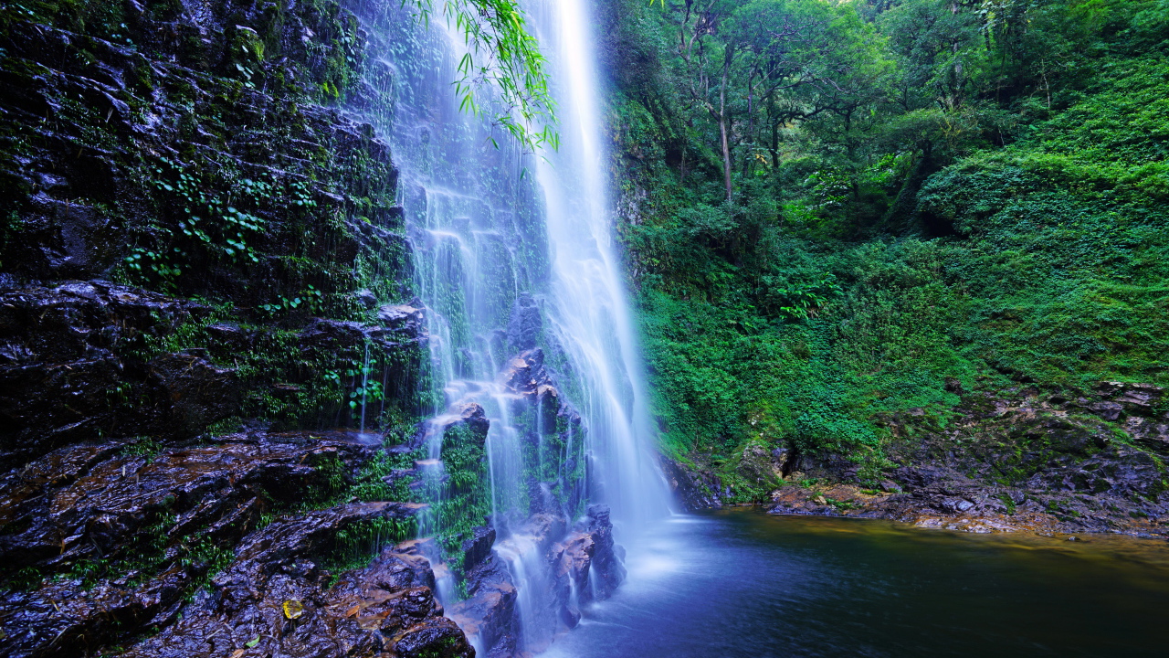 Быстрый водопад стекает по мокрым камням со скалы