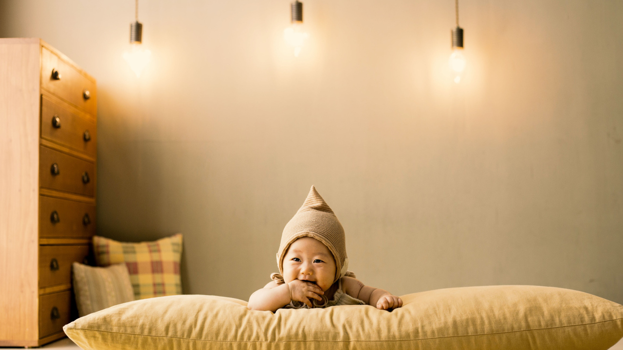 Маленький ребенок лежит на подушке под лампами