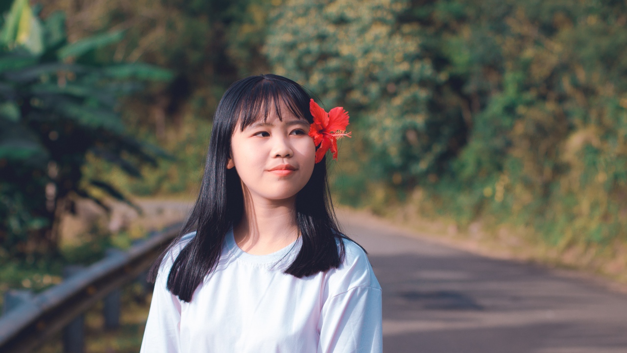 Девушка азиатка с красным цветком гибискуса в волосах