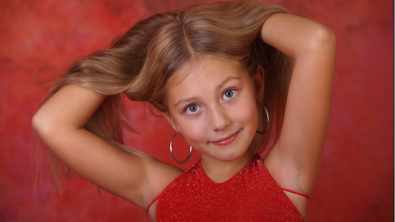 Красивая маленькая девочка с руками в волосах
