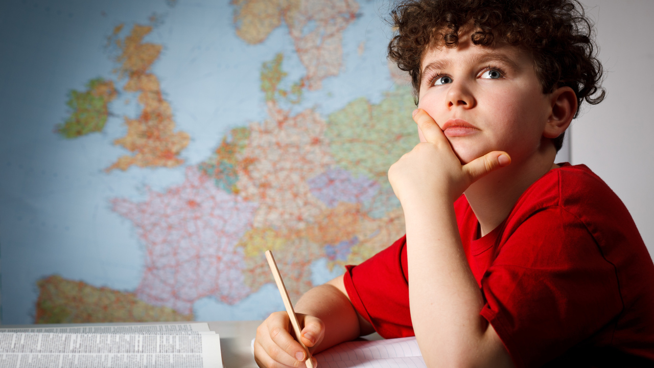 Мальчик ученик делает уроки за столом 