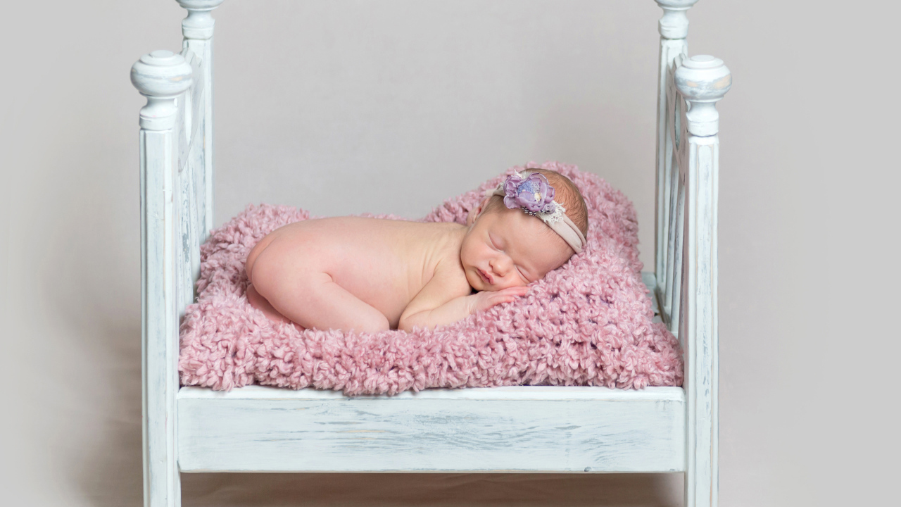 Милый грудной ребенок спит в маленькой кроватке на сером фоне