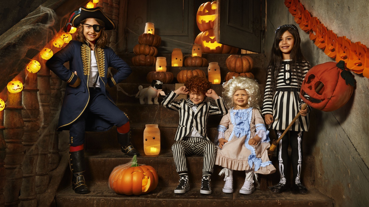 Дети в костюмах на Хэллоуин с тыквами на ступеньках