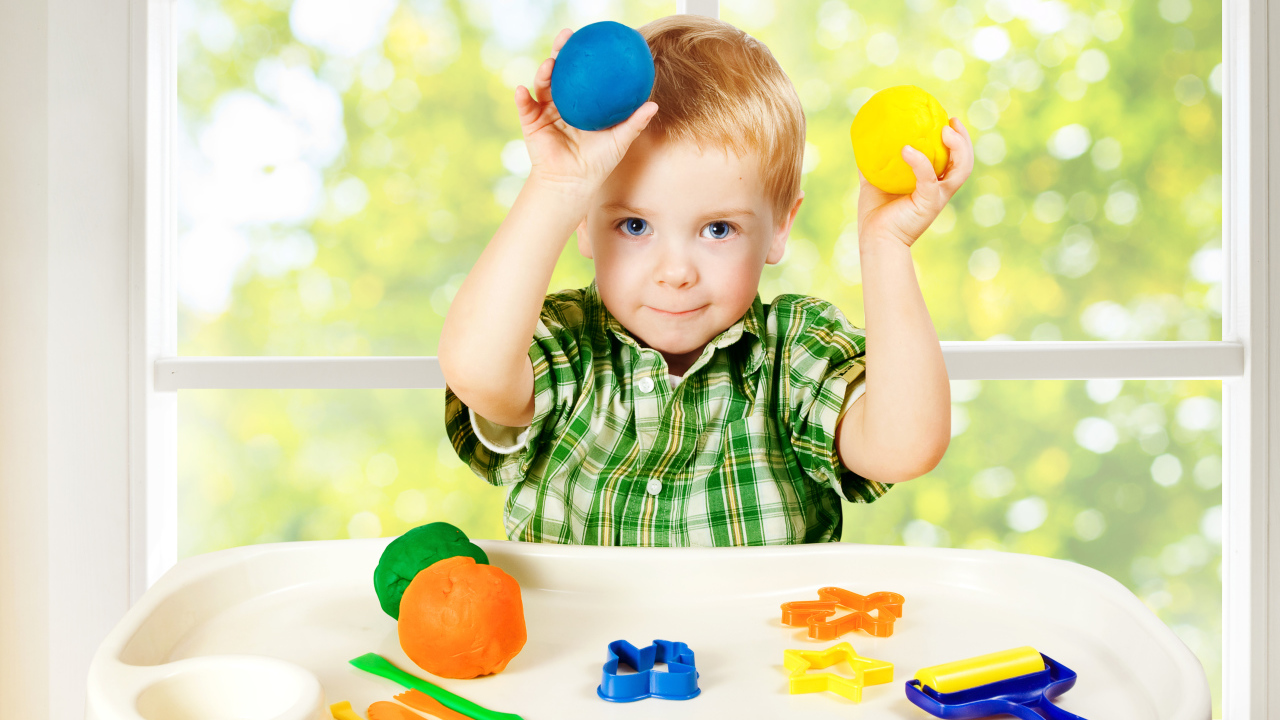 Маленький мальчик играет с игрушками у окна