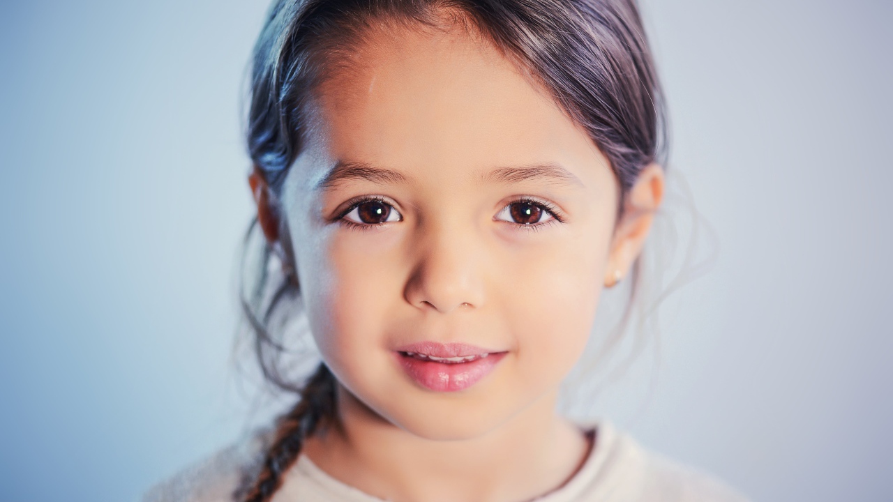 Маленькая кареглазая девочка на сером фоне