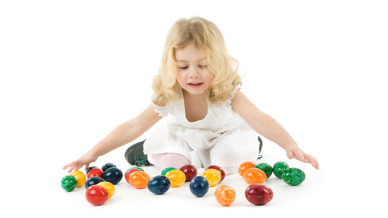 Маленькая девочка блондинка с крашеными яйцами на белом фоне