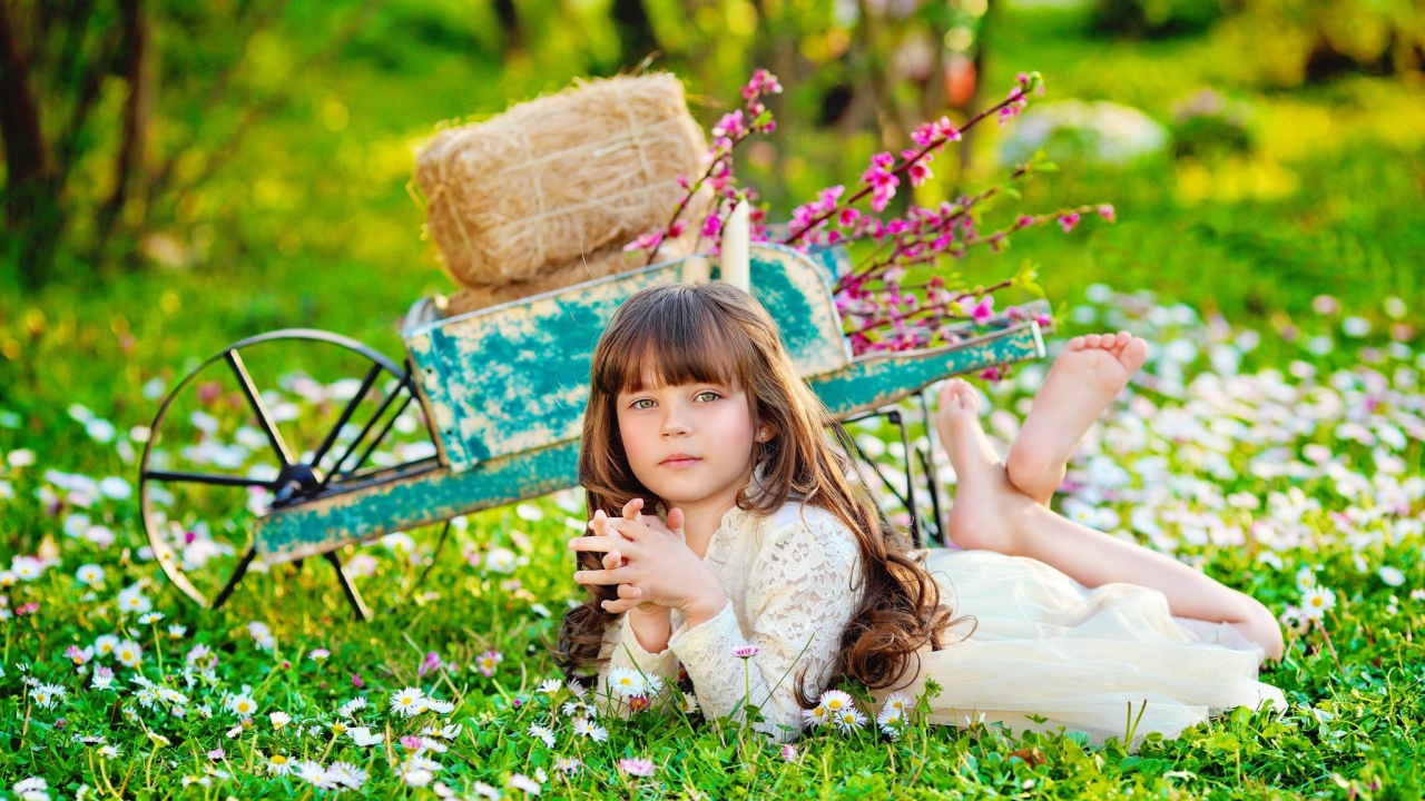 Маленькая девочка лежит на зеленой траве 