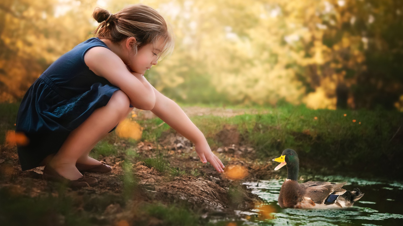 Маленькая девочка играет с уточкой в воде