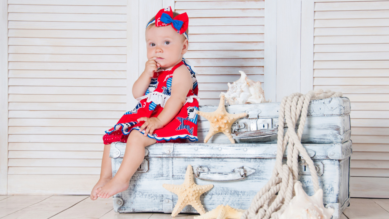 Маленькая девочка сидит на чемодане с морскими звездами