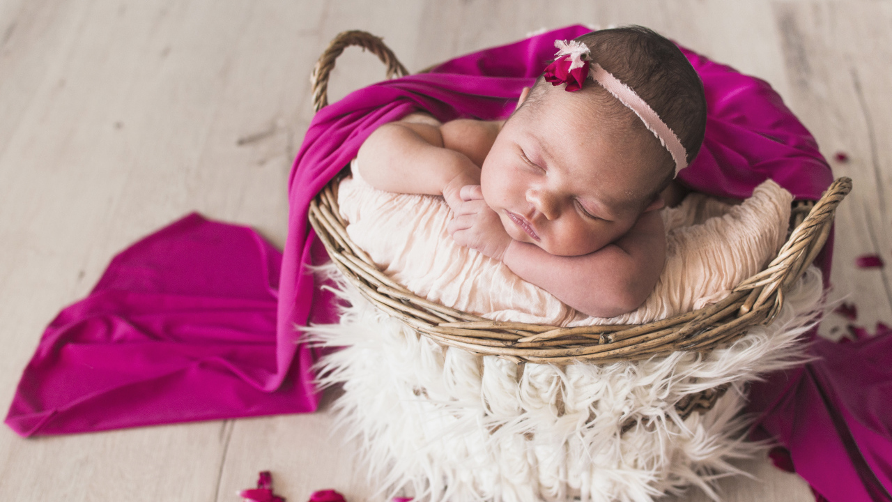 Маленькая девочка спит в корзине под покрывалом