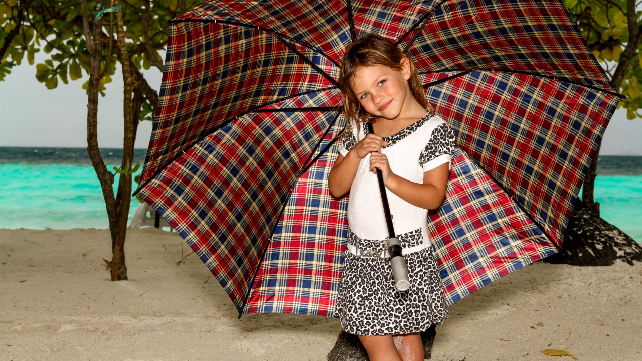 Маленькая девочка с большим зонтом на пляже