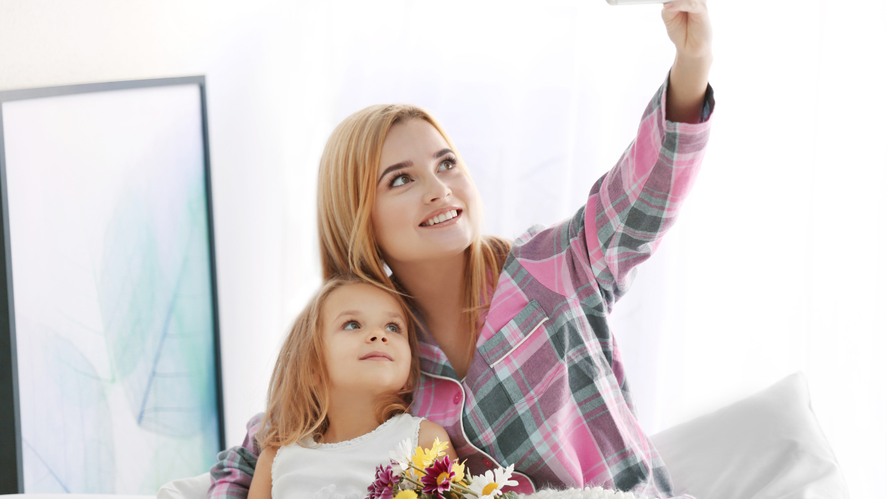 Маленькая девочка с мамой делают фото на смартфон