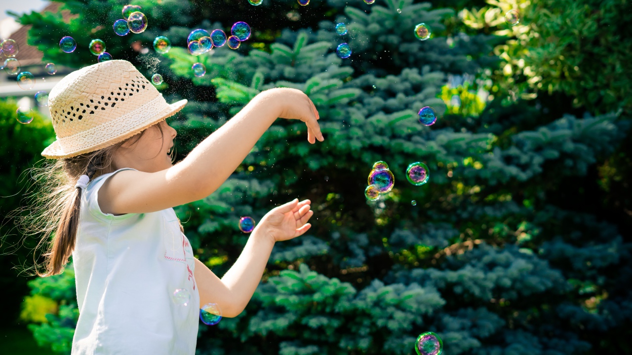 Маленькая девочка с мыльными пузырями у елки
