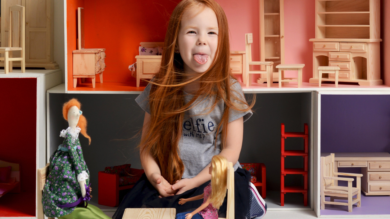 Маленькая длинноволосая девочка показывает язык