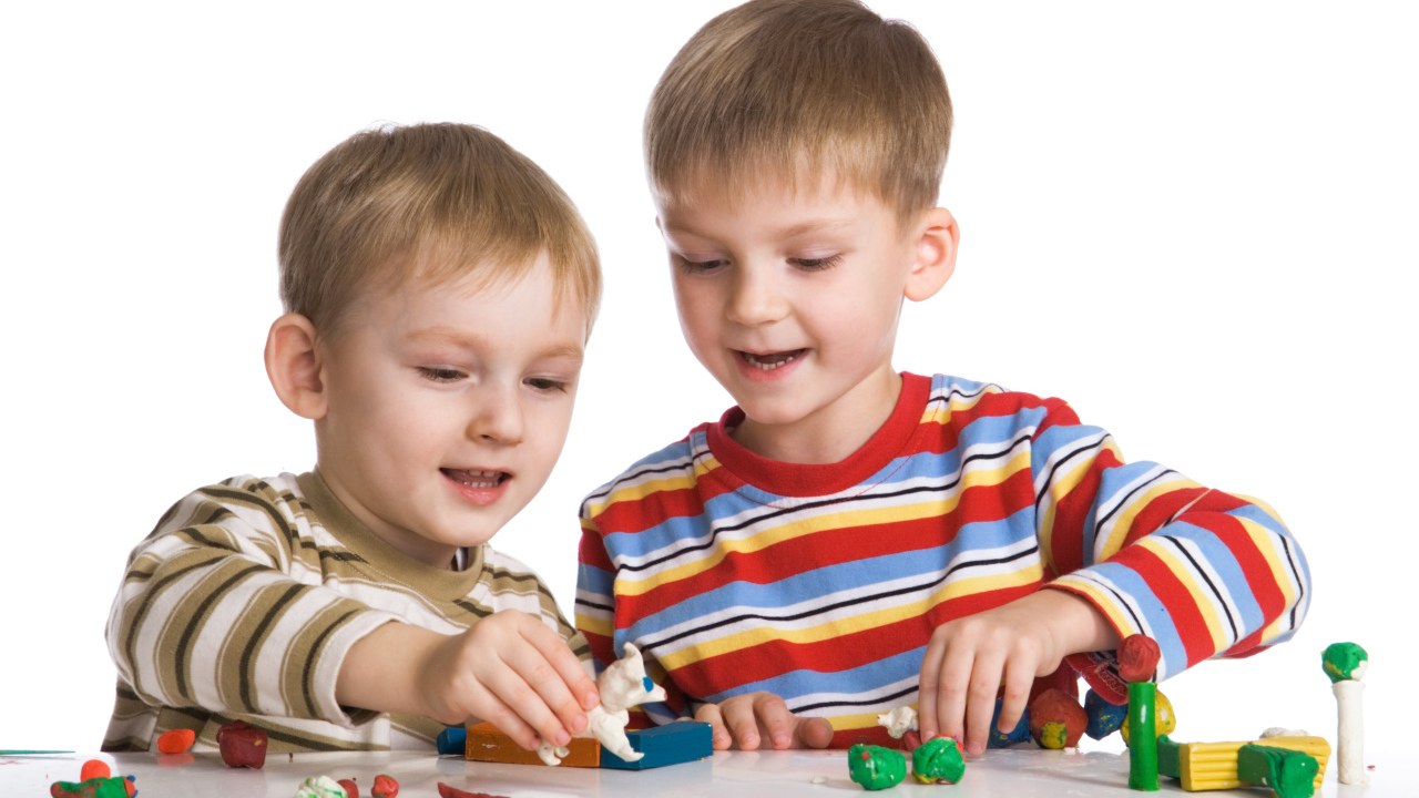 Два мальчика играют в игрушки на белом фоне