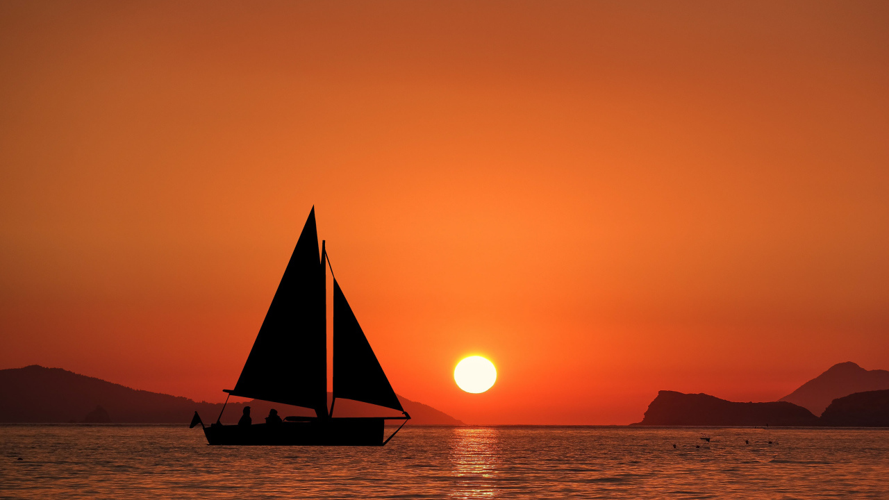 Парусная лодка в море на закате солнца