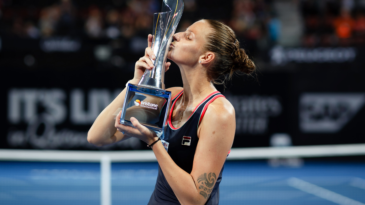 Чешская теннисистка Каролина Плишкова целует кубок на корте