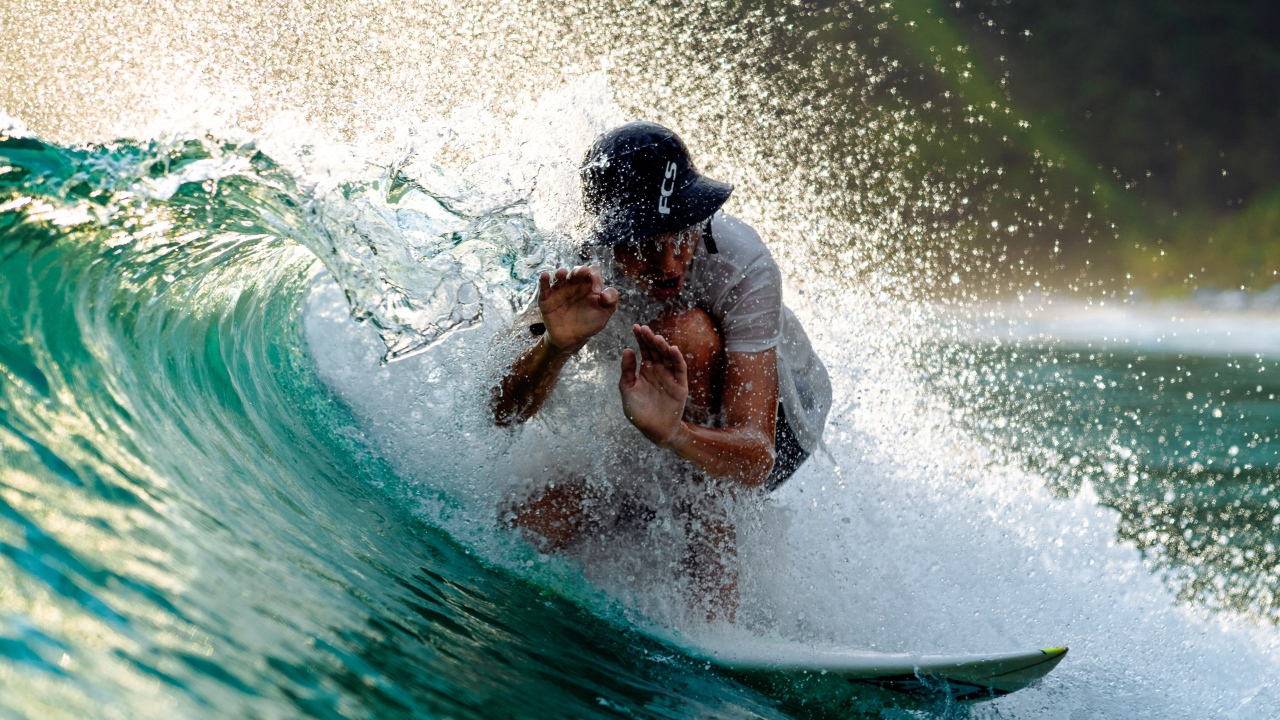 Парень серфингист ловит голубую морскую волну