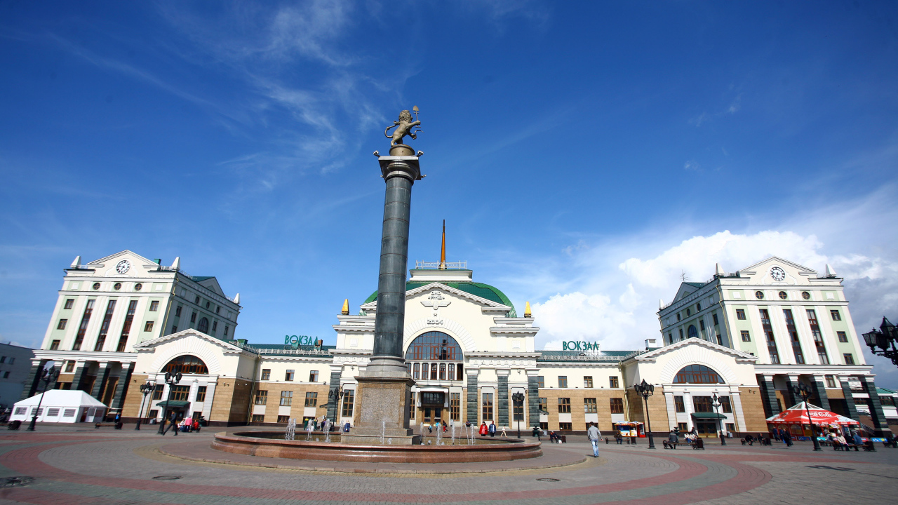Памятник у здания железнодорожного вокзала под красивым голубым небом, Красноярск. Россия