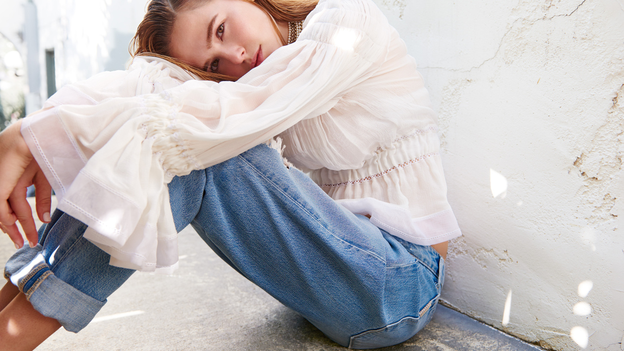 Актриса Зои Дойч сидит у стены