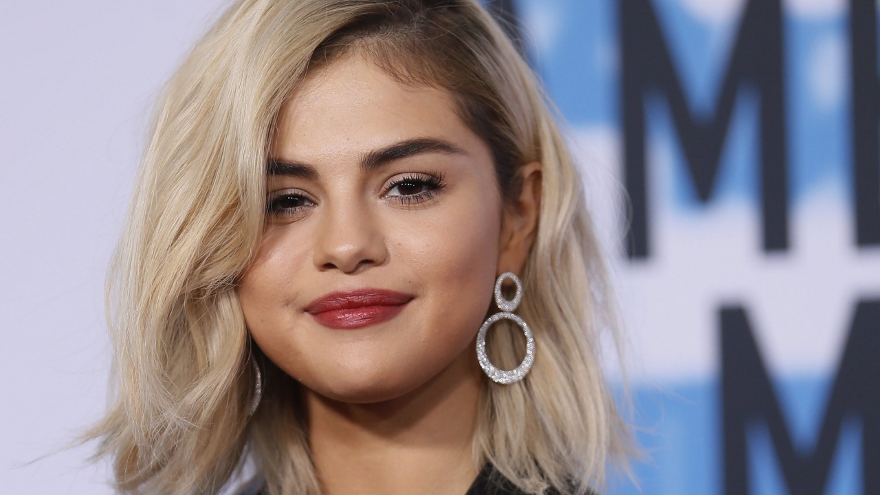 Красивая блондинка, актриса Селена Гомес с серьгами в ушах