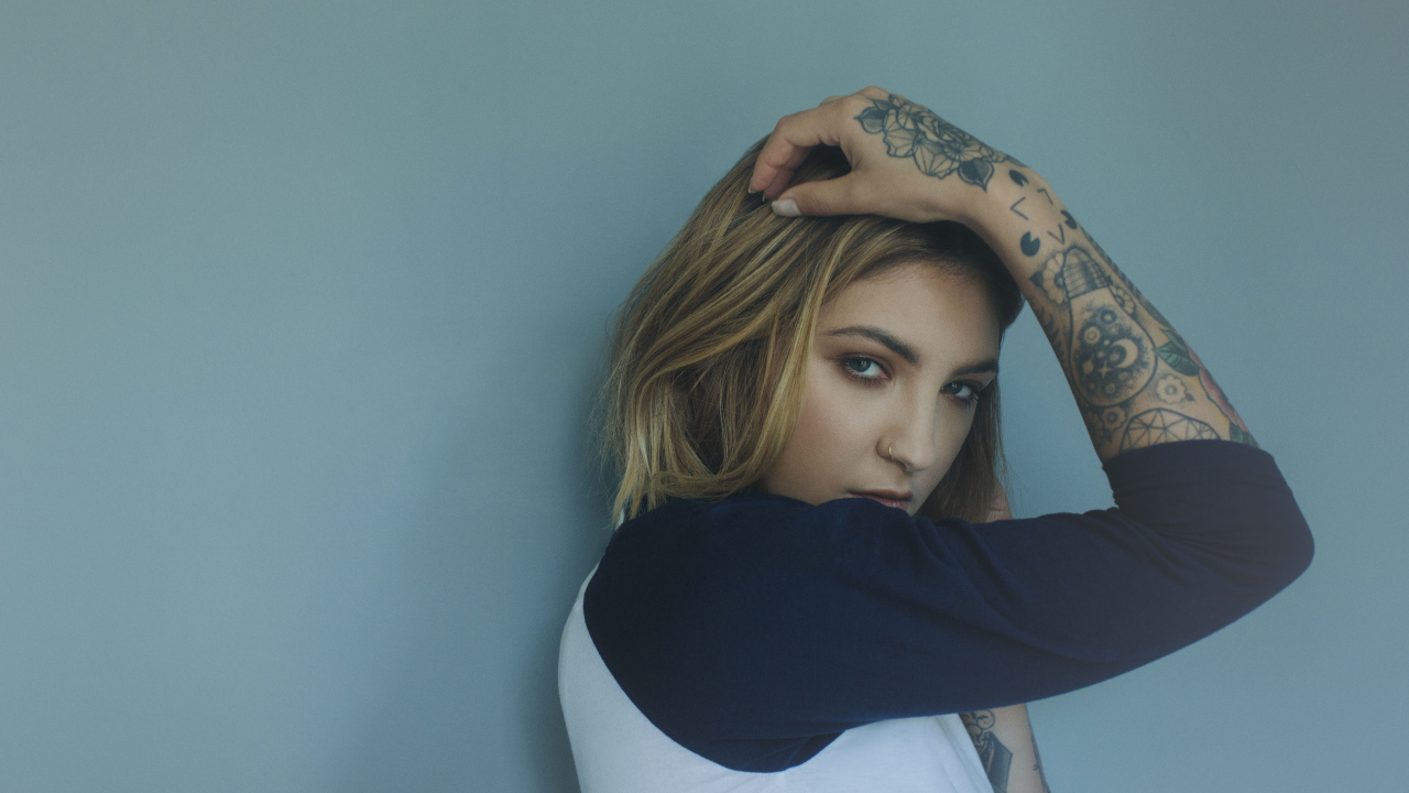 Красивая девушка стоит с татуировками на руке 