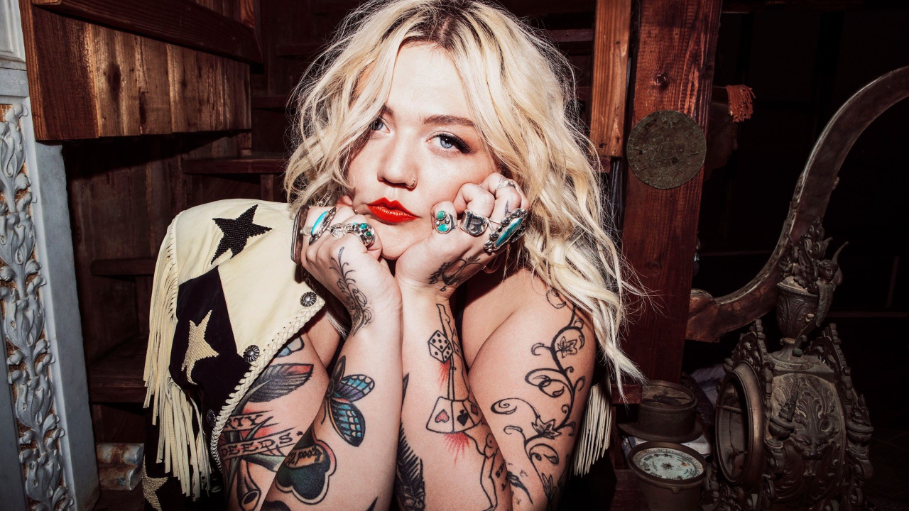 Голубоглазая блондинка с татуировками на руках