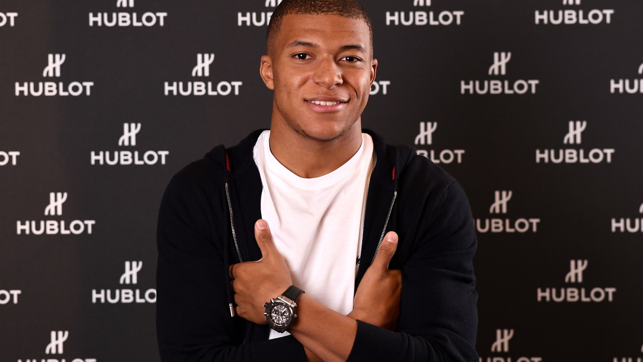 Футболист Килиан Мбаппе в костюме с часами на руке