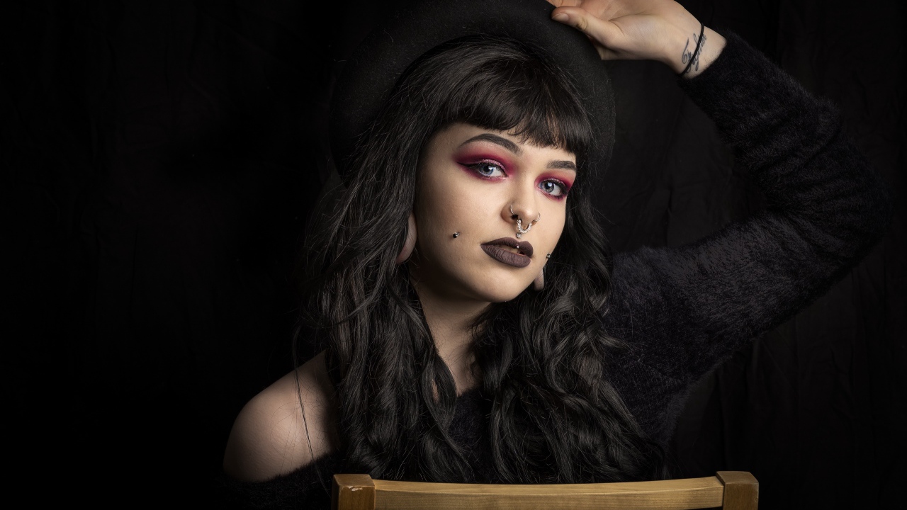 Девушка неформалка с черной шляпе с пирсингом на лице